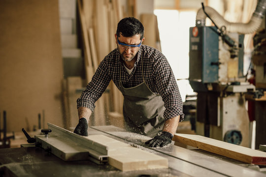 Skilled carpenter cutting a piece of wood in his woodwork workshop