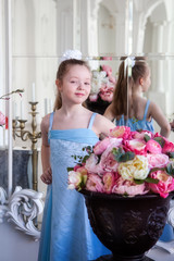 Girl in blue dress is standing in a large room with flowers