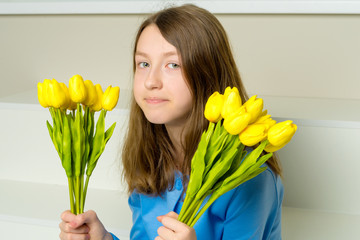 A little girl with a bouquet of tulips is sitting on the stairs.