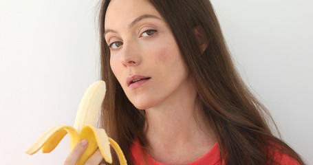 Attractive woman peeling and eating a big banana