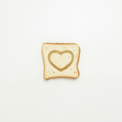 Slice of toast with a heart on a white background.