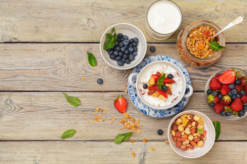 Bowl of homemade granola with yogurt and fresh berries on wooden background