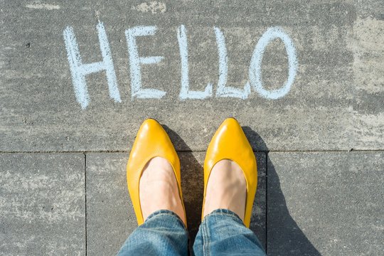 Female feet with text hello written on asphalt