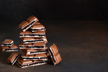 Milk chocolate with vanilla cream and chocolate cookies on a dark background. © zefirchik06