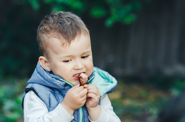 baby, little boy eating a piece of shish kebab meat, outdoors