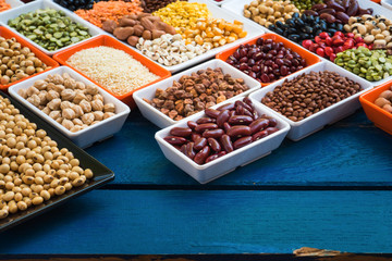 Different dry legumes in container on blue plank, Prepared multicolor dried beans ontable for cooking