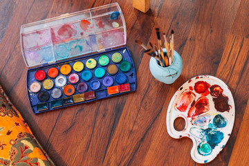 Artist paint brushes and palette on wooden background. Horizontal photo