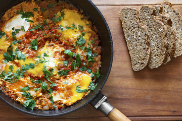 Fried eggs in a frying pan with cereal bread. Shakshuka view from above.