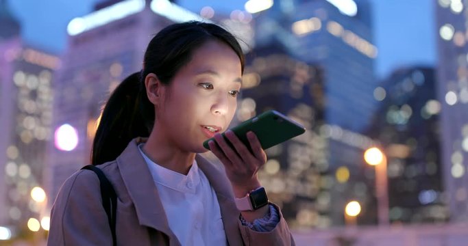 Business woman send audio message on cellphone at night