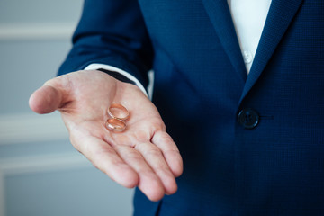 Obraz premium the groom in an elegant suit is holding engagement rings in his hand