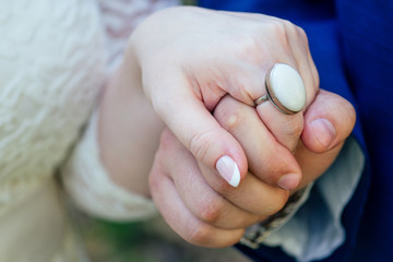 the groom holds the bride's hand with a beautiful large ring with a white stone