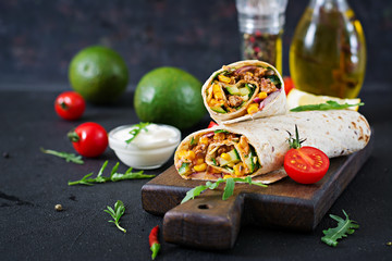 Burritos wraps with beef and vegetables on  black background. Beef burrito, mexican food. - obrazy, fototapety, plakaty
