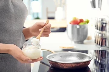 Crédence de cuisine en verre imprimé Cuisinier Femme mettant de l& 39 huile de noix de coco sur une poêle à frire dans la cuisine, gros plan