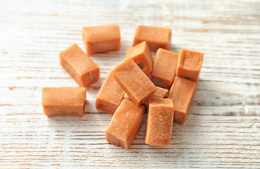 Delicious caramel candies on wooden background