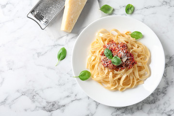 Plate with delicious pasta bolognese on marble background, top view