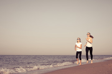 Mother and daughter running on the beach at the day time.