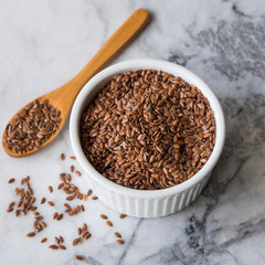 Flax seeds in white ramekin on marble board