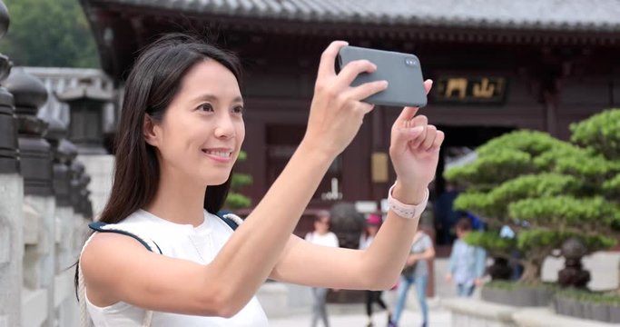 Travel woman use of smart phone to take phone and video in Chinese garden