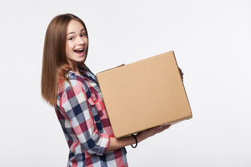 Delivery, relocation and unpacking. Excited young woman holding cardboard box, looking at camera, surprised, isolated