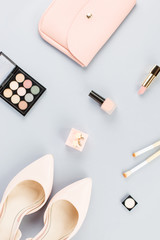 Fashion blogger workspace flat lay with pumps, cosmetics, purse and flowers.