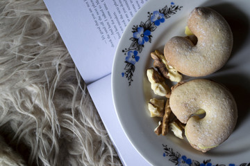 Cake and nuts in a plate against a book background. Close up.