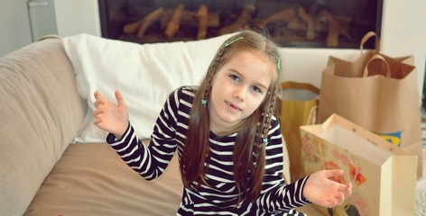 Blond girl, 8 years old, with a happy smile, standing on the sofa, indoor, front view portrait, selective focus