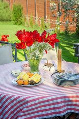 Beautiful bouquet of red tulips in a transparent vase on a table outdoors