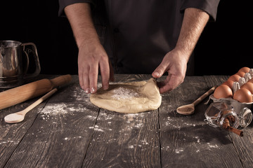 Soft elastic dough in Baker's hands isolated on black