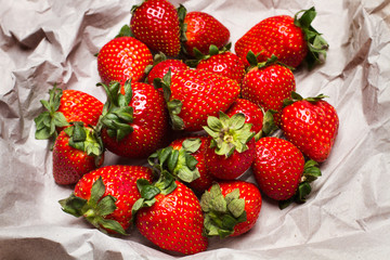 Fresas frescas y naturales sobre papel gris arrugado. Vista superior