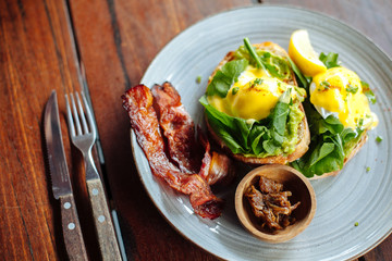 Close up Healthy Breakfast with Wholemeal Bread Toast and Poached Egg with salad, avokado and Beckon on wooden textured table