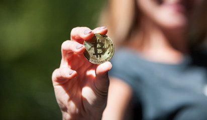 Female hand holding golden bitcoin coin, symbol of crypto currency