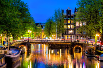 Amsterdam canal with typical dutch houses and bridge during twilight blue hour in Holland, Netherlands. © Nikolay N. Antonov