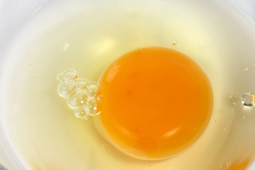 Raw Egg Yolk and white liquid in transparent glass bowl white background