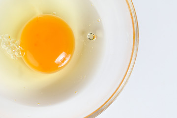 Raw Egg Yolk and white liquid in transparent glass bowl white background