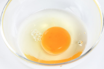 Raw Egg Yolk and white liquid in transparent glass bowl white background