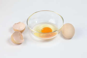 Raw Egg Yolk and white liquid in transparent glass bowl eggshell white background