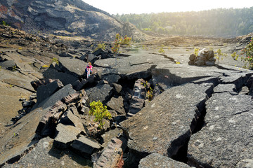 Young female tourist exploring surface of the Kilauea Iki volcano crater with crumbling lava rock in Volcanoes National Park in Big Island of Hawaii © MNStudio
