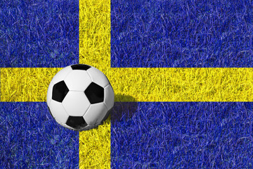 Fototapeta premium Black and white soccer ball on a meadow / grass painted in colors of national flag of Sweden, copy space for text, concept football