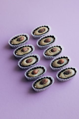 Three delicious praline sweets with almonds on purple background