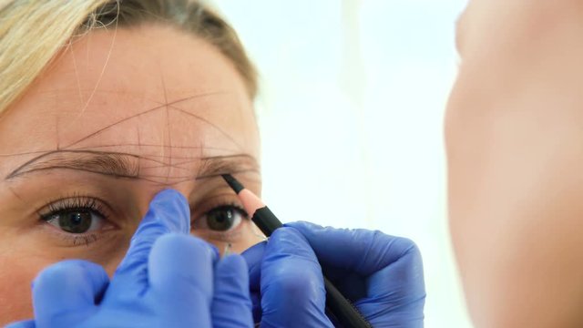 Cosmetologist preparing woman for eyebrow permanent makeup procedure, closeup