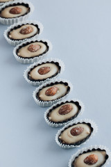 Row of delicious praline sweets with almonds on blue background