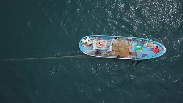 4k aerial of fishermen throwing a drift fishing net in the sea from a blue boat