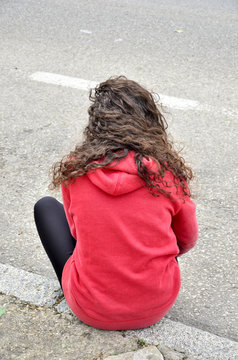 Chica sentada en un bordillo