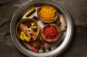 a variety of spices on a tray on a wooden background.