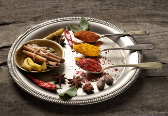 a variety of spices on a tray on a wooden background.