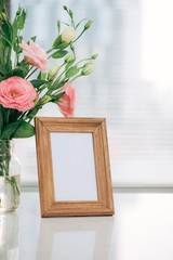 Mother's Day, Women's Day or other suitable holiday card in rectangular photo frame with blank space for your text on white table with Lisianthus flowers bouquet in glass bottle and paraffin candle
