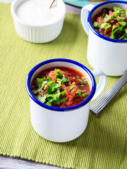 Russian beetroot soup borscht in enamel mugs on green cloth