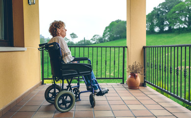 Serious older woman in a wheelchair in the porch