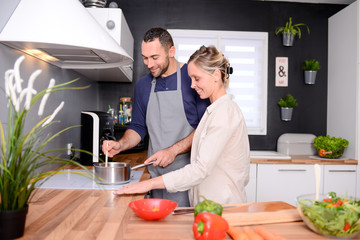 happy and cheerful young couple cooking organic vegetables together at home