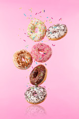 Flying sweet donuts isolated on pink background.